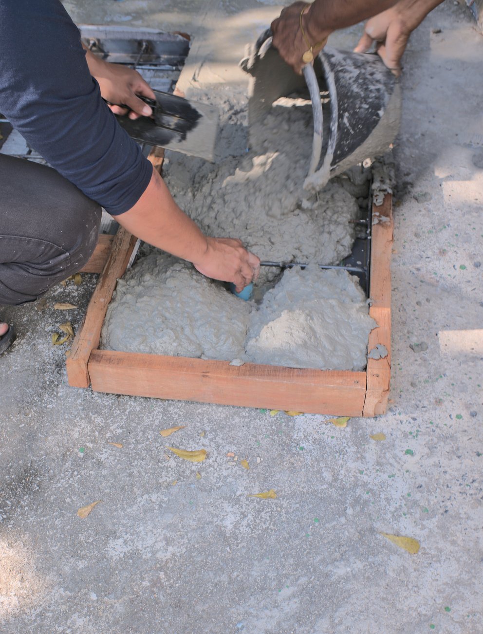 Pour concrete on the floor Concrete formwork, concrete pouring tank, construction worker, Hand of worker use trowel plastering a newly poured concrete on construction site. Leveling concrete with trowels,manhole cover